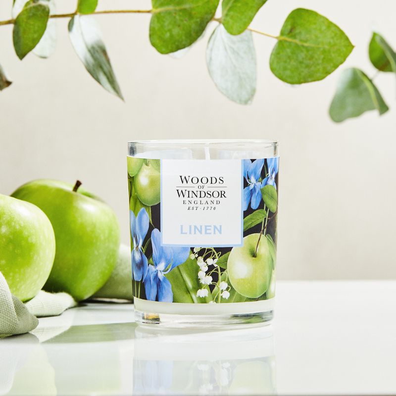 Candle next to apples and eucalyptus branch.