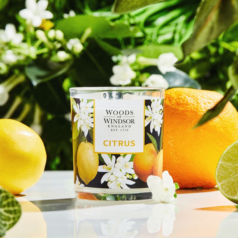 Citrus candle next to a big orange and jasmine flower.