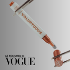 A cosmetic applicator pen labeled 'VOLUPTUOUS' and 'MADAME J' is shown floating diagonally between two metal tweezers against a light gray gradient background, with 'AS FEATURED IN VOGUE' text in the lower left.