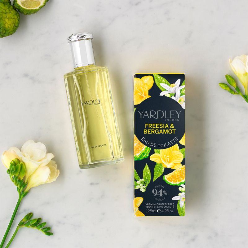 Vegan eau de toilette bottle next to box and freesia flowers.